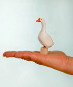 Adult hand holding the Bumbu handcrafted wooden white decorative figure showing size