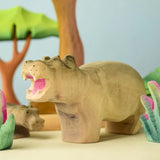 Bumbu toys handcrafted wooden grey standing hippo figure in a playscene with trees in the background