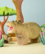 Bumbu toys handcrafted wooden grey standing hippo figure in a playscene with trees in the background