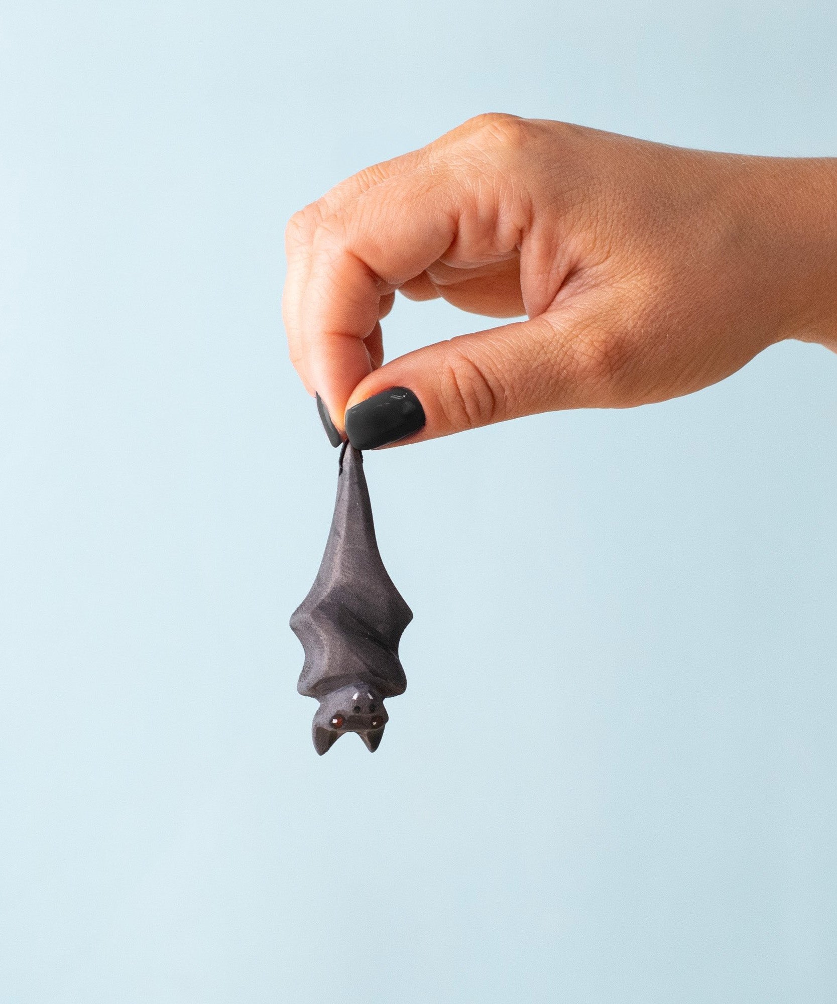Bumbu Toys Wooden bat figure hanging upside down and held in an adult's hand to show scale.  Fab halloween small world play  handmade toys, full range available at babipur