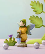 A Bumbu winged elf holding a wooden lantern. Bumbu flowers and trees can be seen in the background.