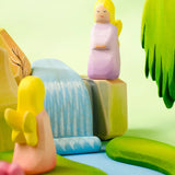 A playscene showing a Bumbu handcrafted wooden lavender fairy figure on top of rocks and a small waterfall