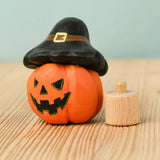 Bumbu handcrafted wooden magic pumpkin decorative figure wearing a black hat next to a small display peg