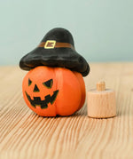Bumbu handcrafted wooden magic pumpkin decorative figure wearing a black hat next to a small display peg