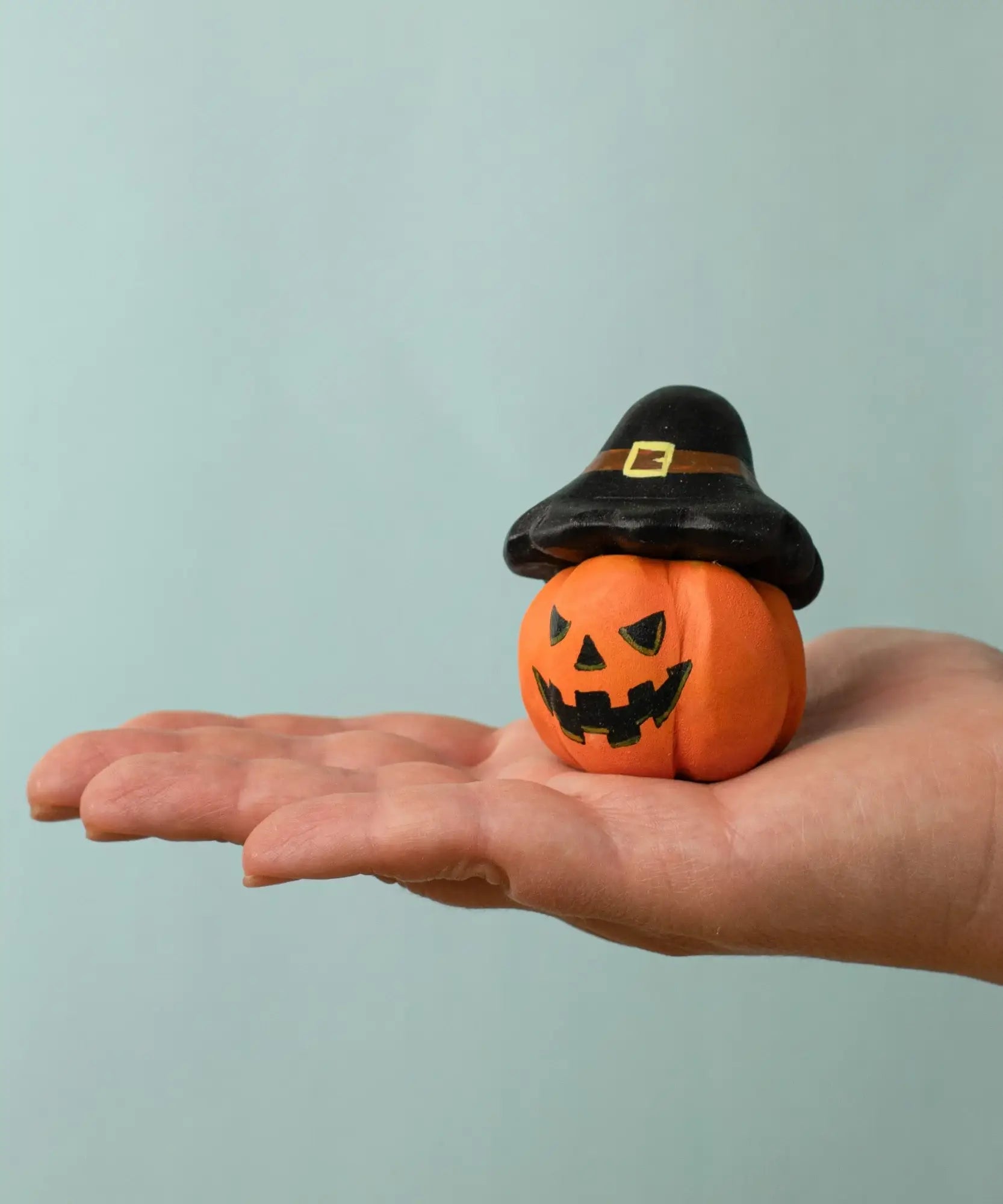 Bumbu handcrafted wooden magic pumpkin decorative figure on a adult hand showing scale