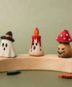 Bumbu handcrafted wooden magic red candle displayed on a celebration ring in between a spooky ghost and mushroom figure