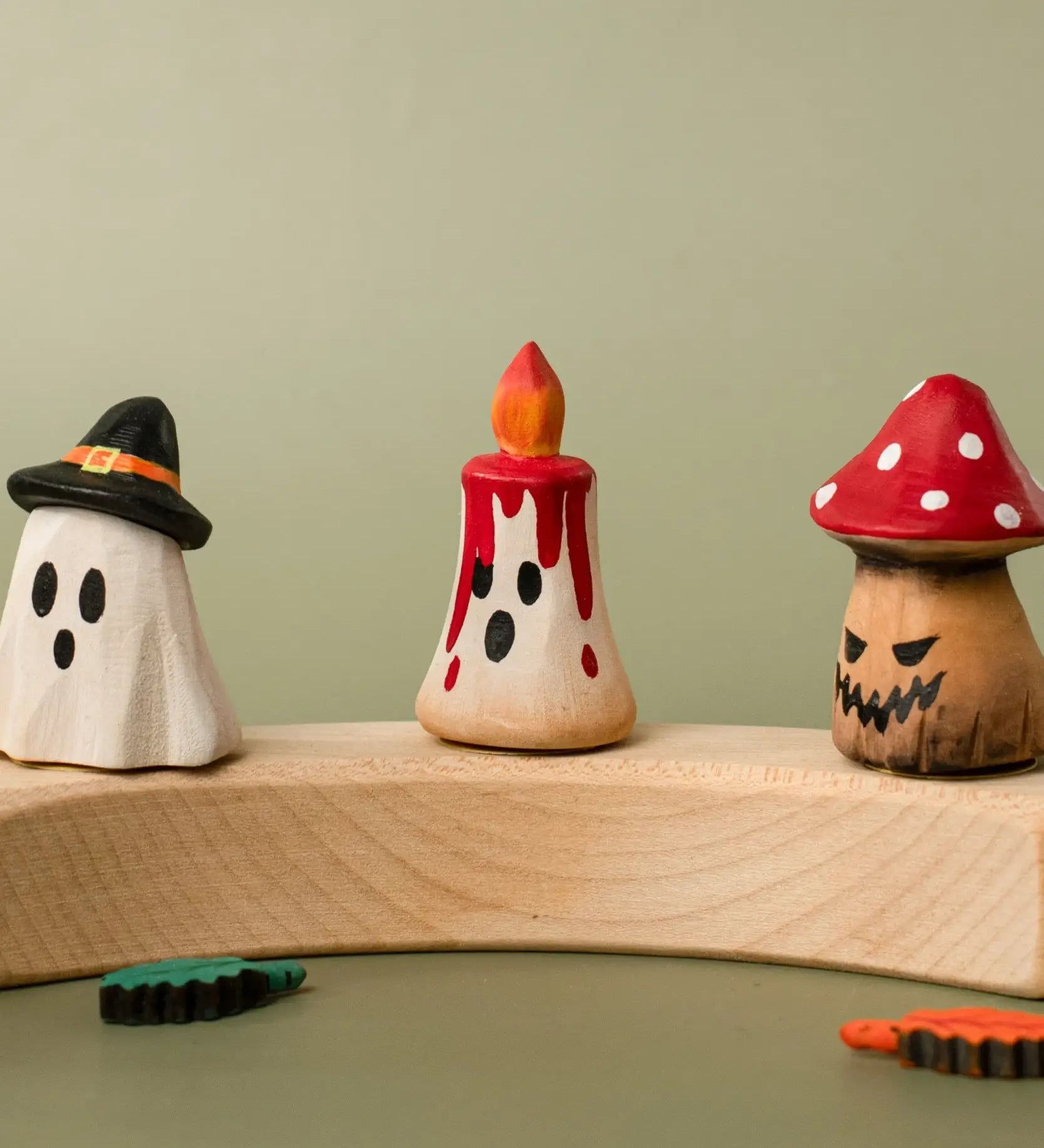 Bumbu handcrafted wooden magic red candle displayed on a celebration ring in between a spooky ghost and mushroom figure