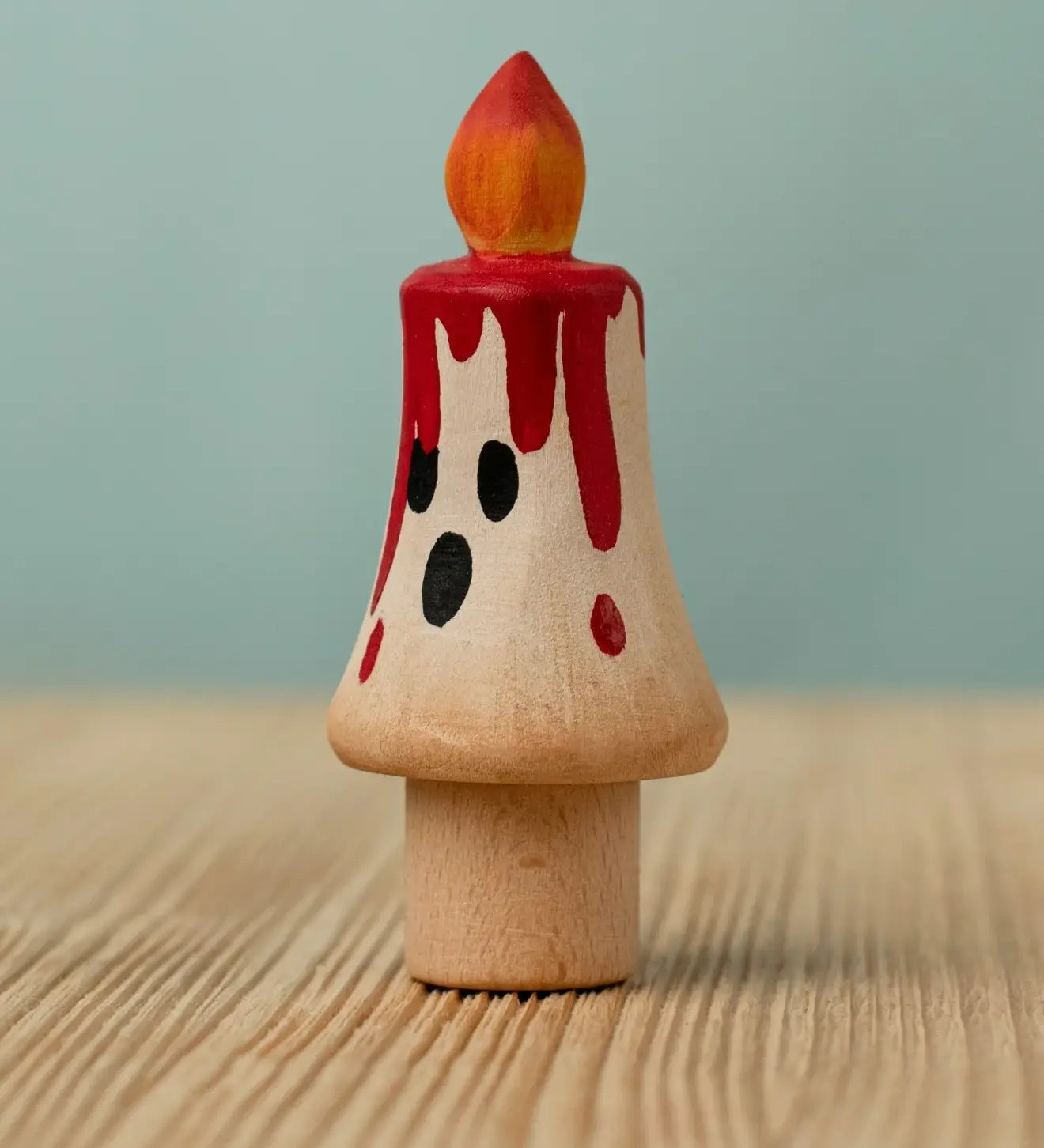 Bumbu handcrafted wooden magic candle with a friendly face and painted red dripping wax
