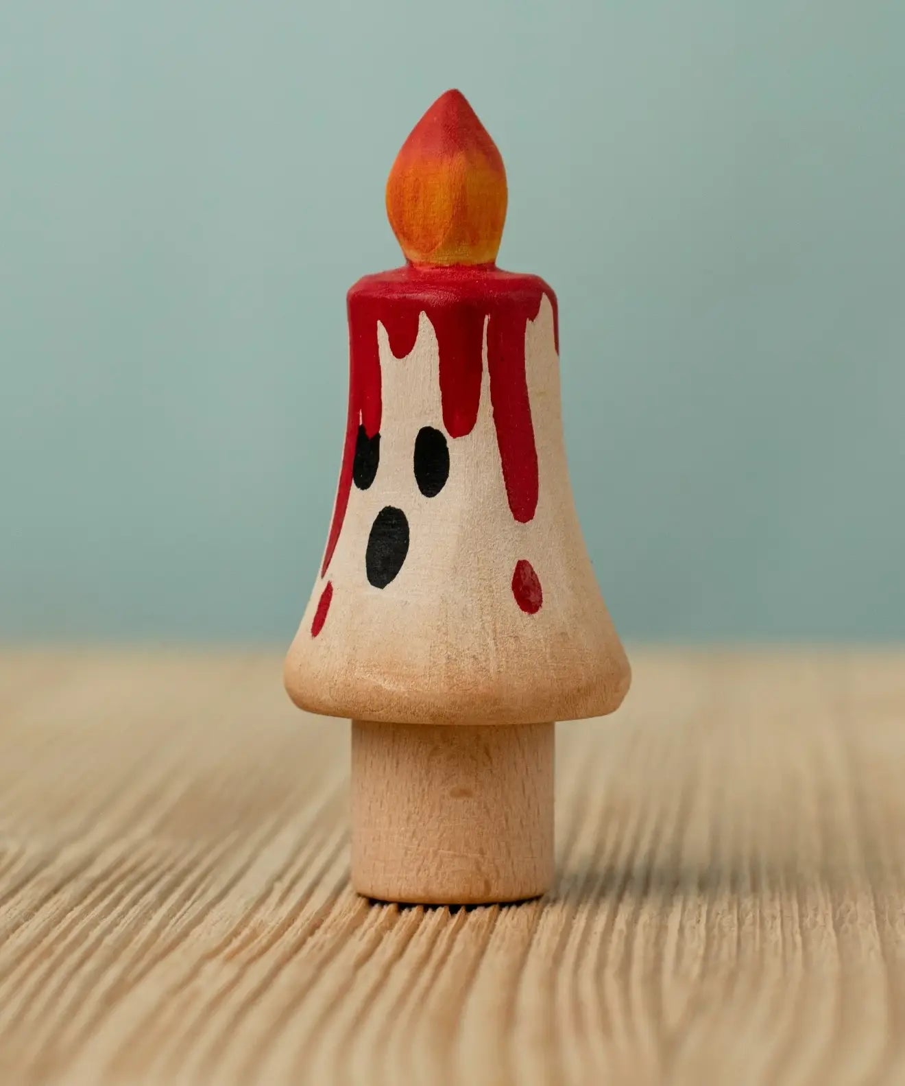 Bumbu handcrafted wooden magic candle with a friendly face and painted red dripping wax