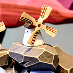 Bumbu Miniature Wooden Moldova Windmill. The toy sits on a wooden surface against a blue background. The blades and mill sit separately.