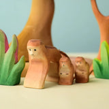 Bumbu toys handcrafted wooden brown standing monkey figures in a playscene with trees in the background