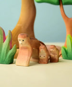 Bumbu toys handcrafted wooden brown standing monkey figures in a playscene with trees in the background