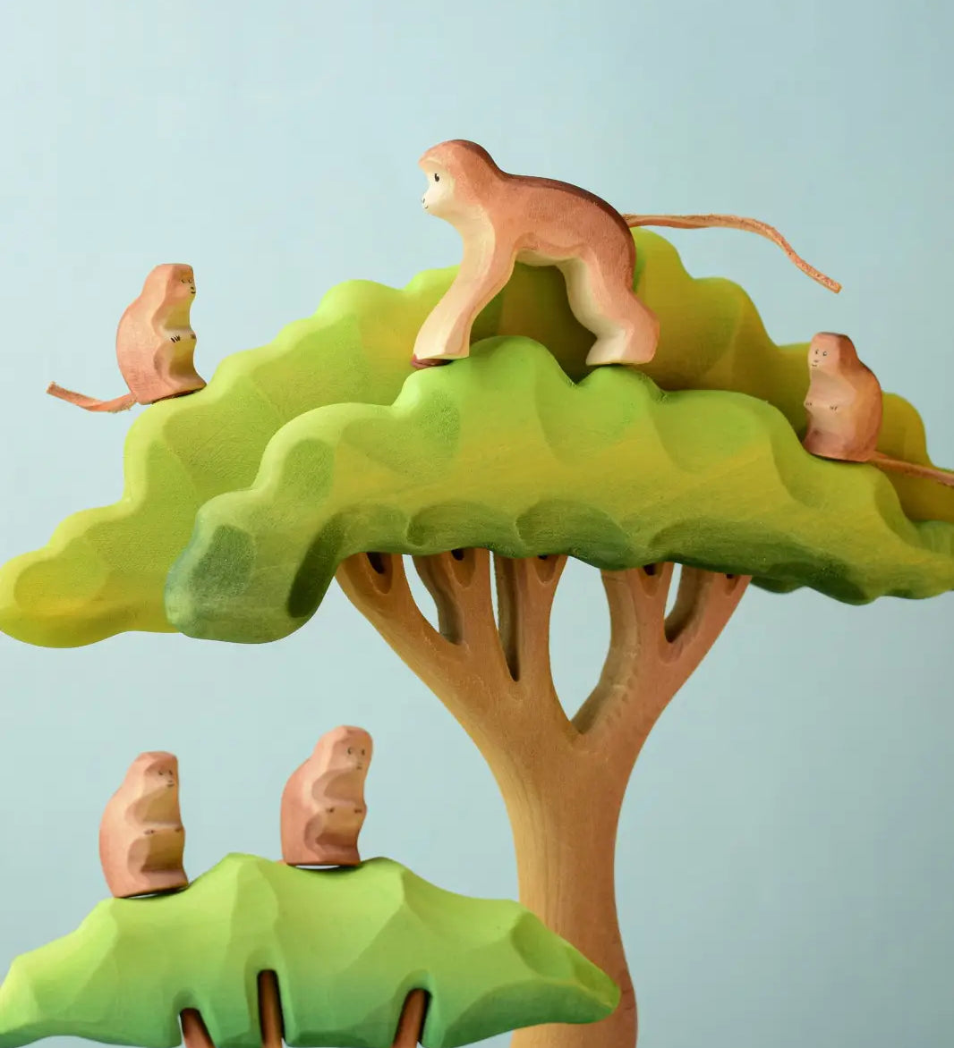 A family of Bumbu toys handcrafted wooden monkey figures standing on a tree set