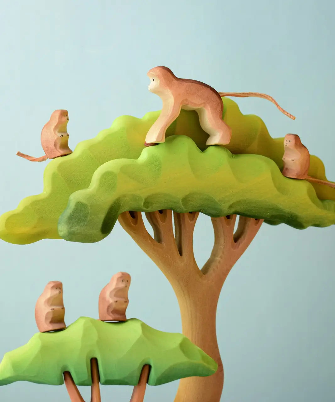 A family of Bumbu toys handcrafted wooden monkey figures standing on a tree set