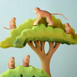 A family of Bumbu toys handcrafted wooden monkey figures standing on a tree set