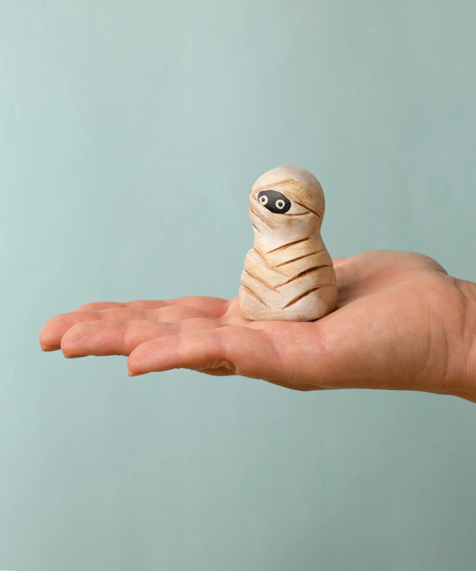 Bumbu handcrafted wooden enchanted mummy decorative figure on an adult hand showing scale