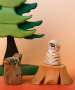 Bumbu handcrafted enchanted mummy decorative figure displayed on a tree stump figure next to a spooky small tree