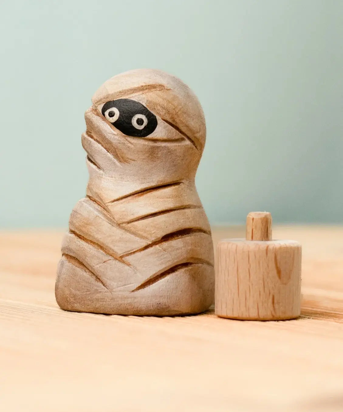 Bumbu handcrafted enchanted mummy decorative figure next to a wooden celebration ring peg