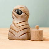 Bumbu handcrafted enchanted mummy decorative figure next to a wooden celebration ring peg