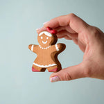 A hand holding the Bumbu wooden gingerbread cookie girl