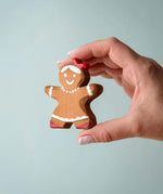 A hand holding the Bumbu wooden gingerbread cookie girl