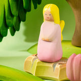 Bumbu wooden pink fairy figure standing on a rock by a pond set