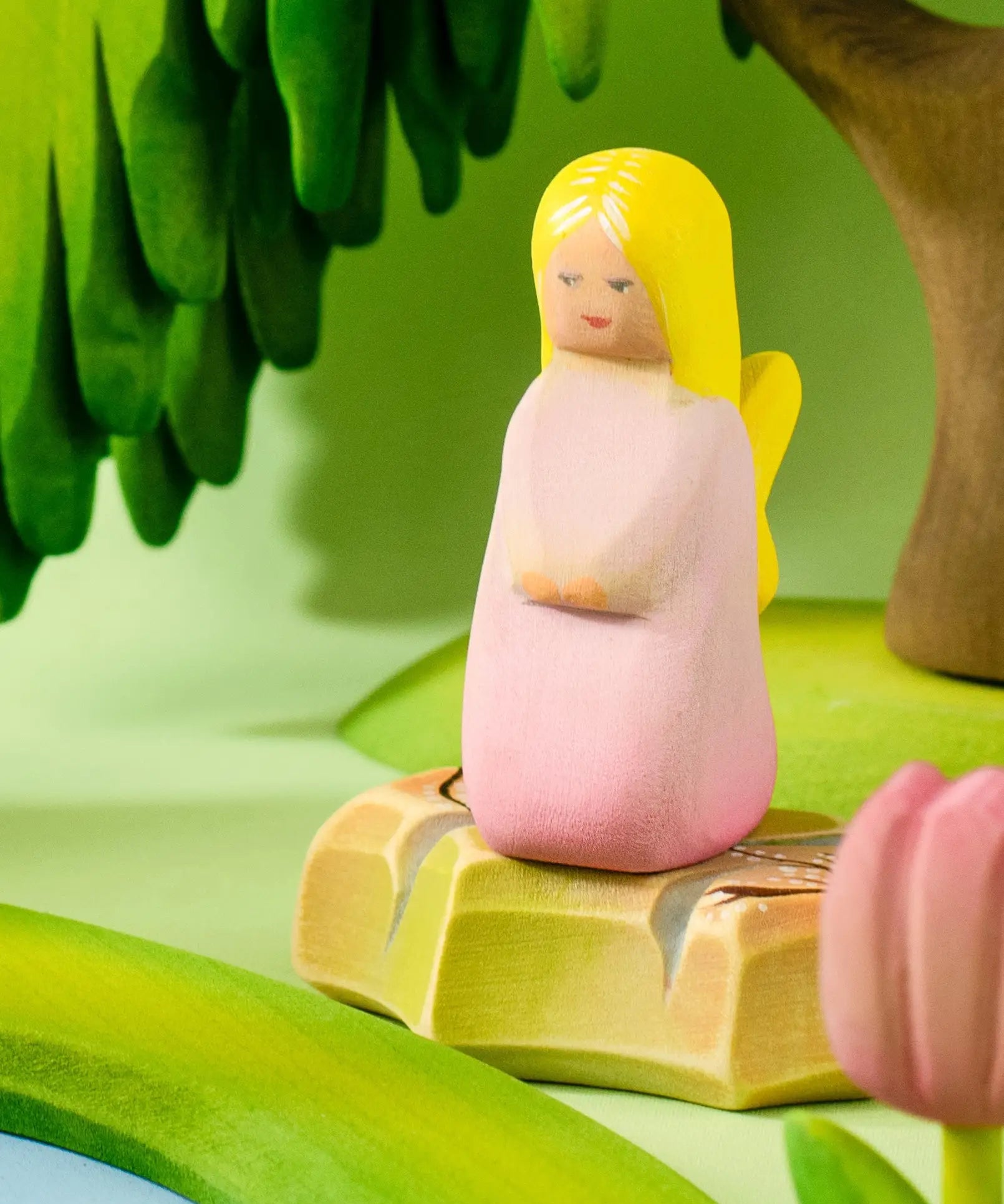 Bumbu wooden pink fairy figure standing on a rock by a pond set