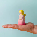 Adult hand holding the Bumbu wooden pink fairy figure showing scale