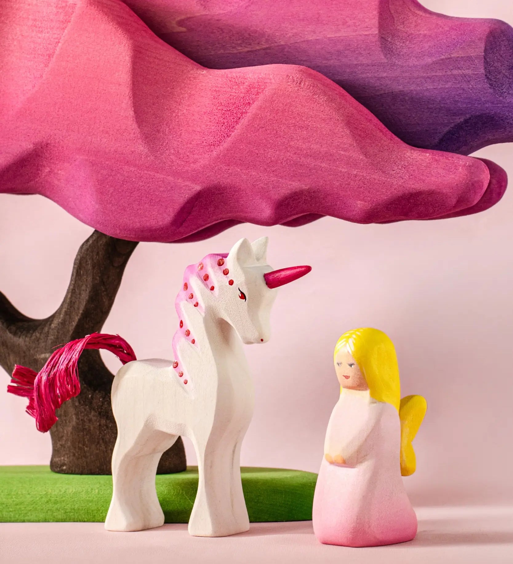 Bumbu wooden pink fairy figure next to a pink unicorn and blossom tree figure