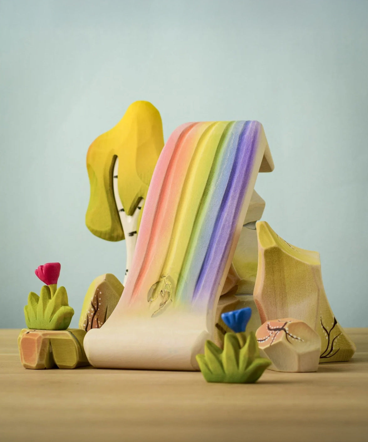 The Bumbu rainbow waterfall shown in a small world play scene with the rainbow rocks and Bumbu flowers and a birch tree. 
