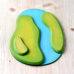 Bumbu Wooden River Base flowing between a blue river and green grass