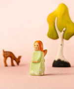 Bumbu wooden sage fairy figure with a eating deer and birch tree in the background