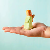 Adult hand holding a Bumbu wooden sage fairy figure showing scale