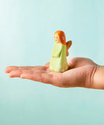 Adult hand holding a Bumbu wooden sage fairy figure showing scale