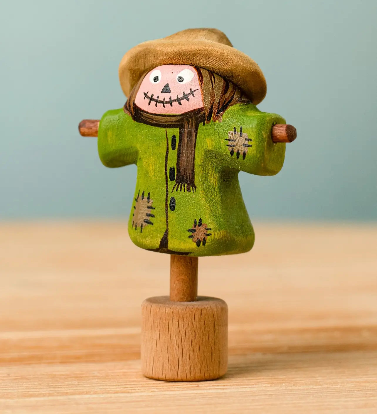 Bumbu handcrafted wooden scarecrow decorative figure with painted detail, wearing a brown hat and standing on a celebration ring peg base