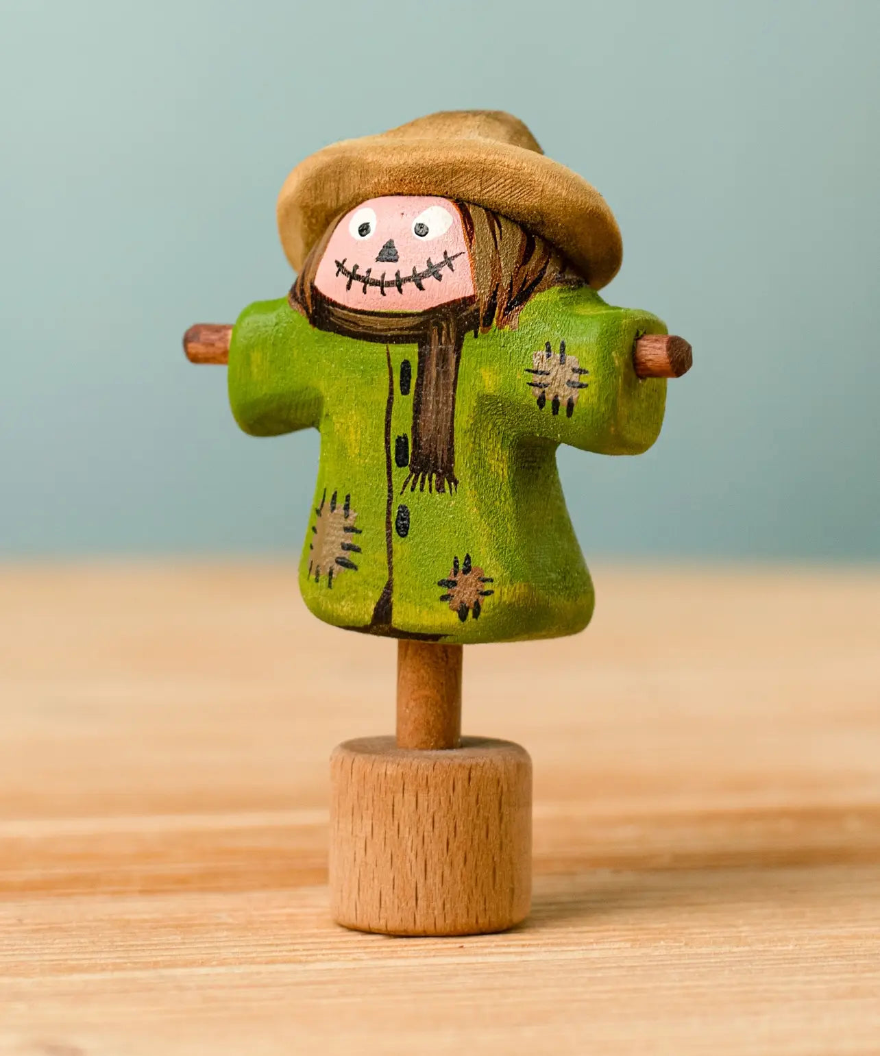 Bumbu handcrafted wooden scarecrow decorative figure with painted detail, wearing a brown hat and standing on a celebration ring peg base