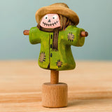 Bumbu handcrafted wooden scarecrow decorative figure with painted detail, wearing a brown hat and standing on a celebration ring peg base