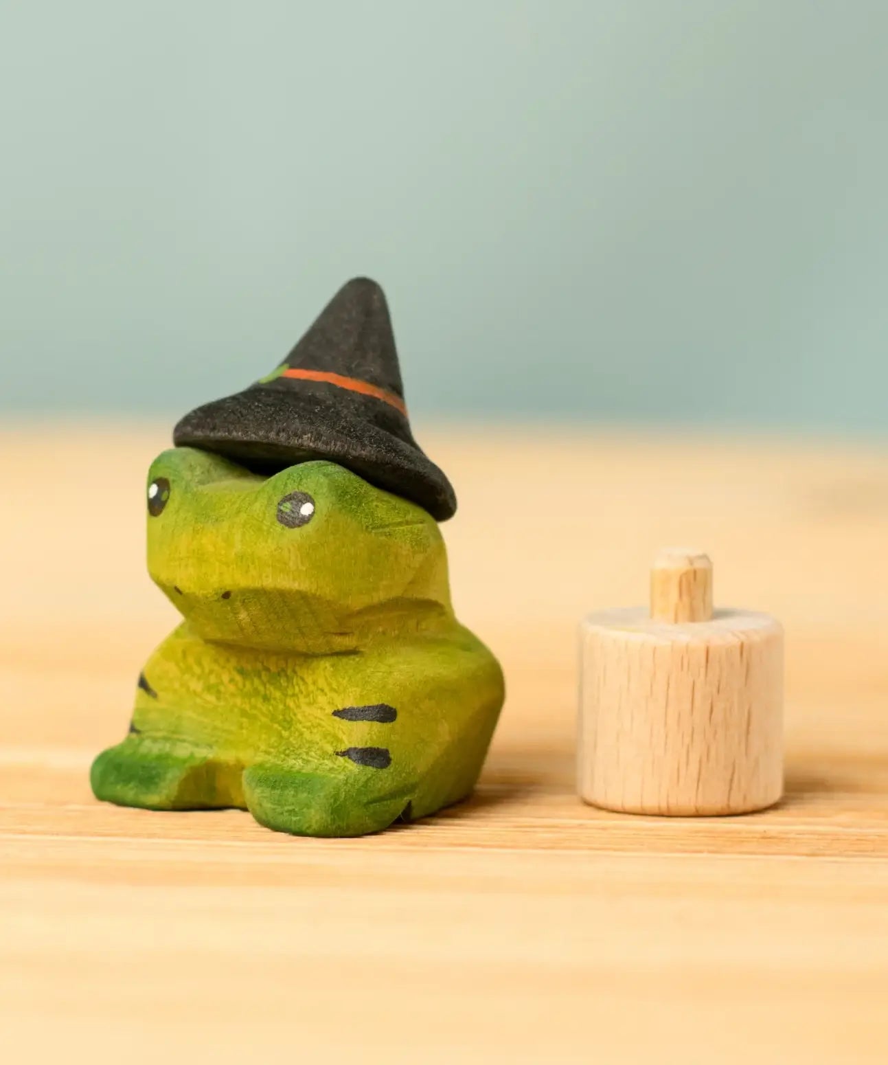 Bumbu handcrafted wooden spell green frog decorative figure next to a celebration ring peg
