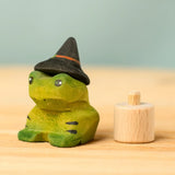 Bumbu handcrafted wooden spell green frog decorative figure next to a celebration ring peg