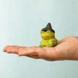 Bumbu handcrafted wooden spell green frog decorative figure on a adult hand showing scale