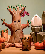 A Bumbu spooky tree set up in a small world play scene with a wooden Bumbu bat hung on one of it's branches. 