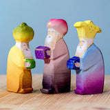 The Bumbu wooden Three Kings figures placed on a wooden surface against a blue background. 