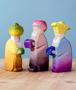 The Bumbu wooden Three Kings figures placed on a wooden surface against a blue background. 
