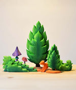 Bumbu wooden shrubs and bushes toy figures placed on a wooden worktop next to the green Thuja tree toy figures. These expertly hand crafted items are part of a large range of wooden toys available here at Babipur. 