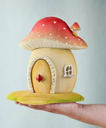 The Bumbu toadstool house shown in and adult's hand.