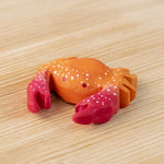 The Bumbu hand carved wooden red crab toy, with white speckled details on its shell