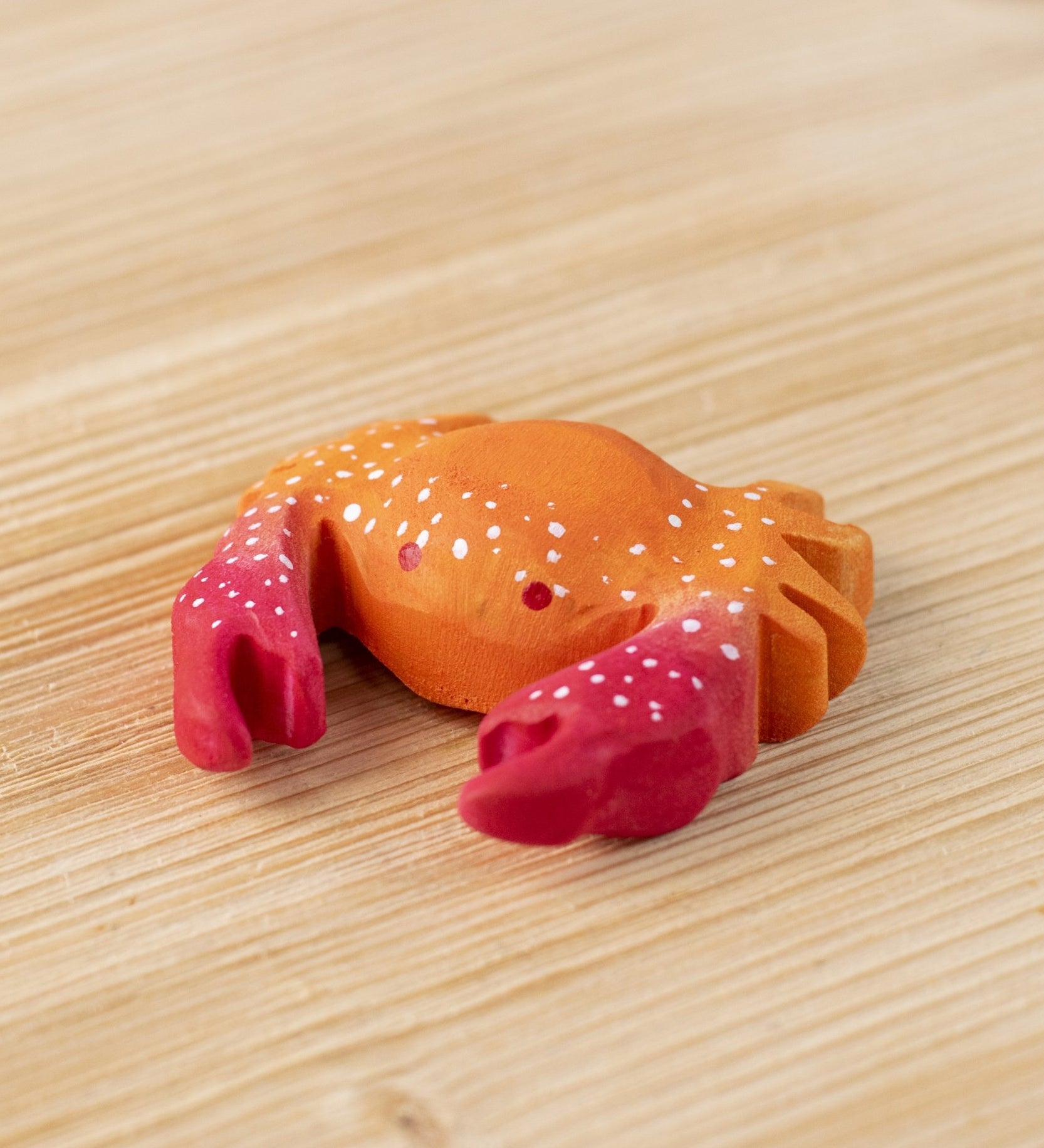 The Bumbu hand carved wooden red crab toy, with white speckled details on its shell