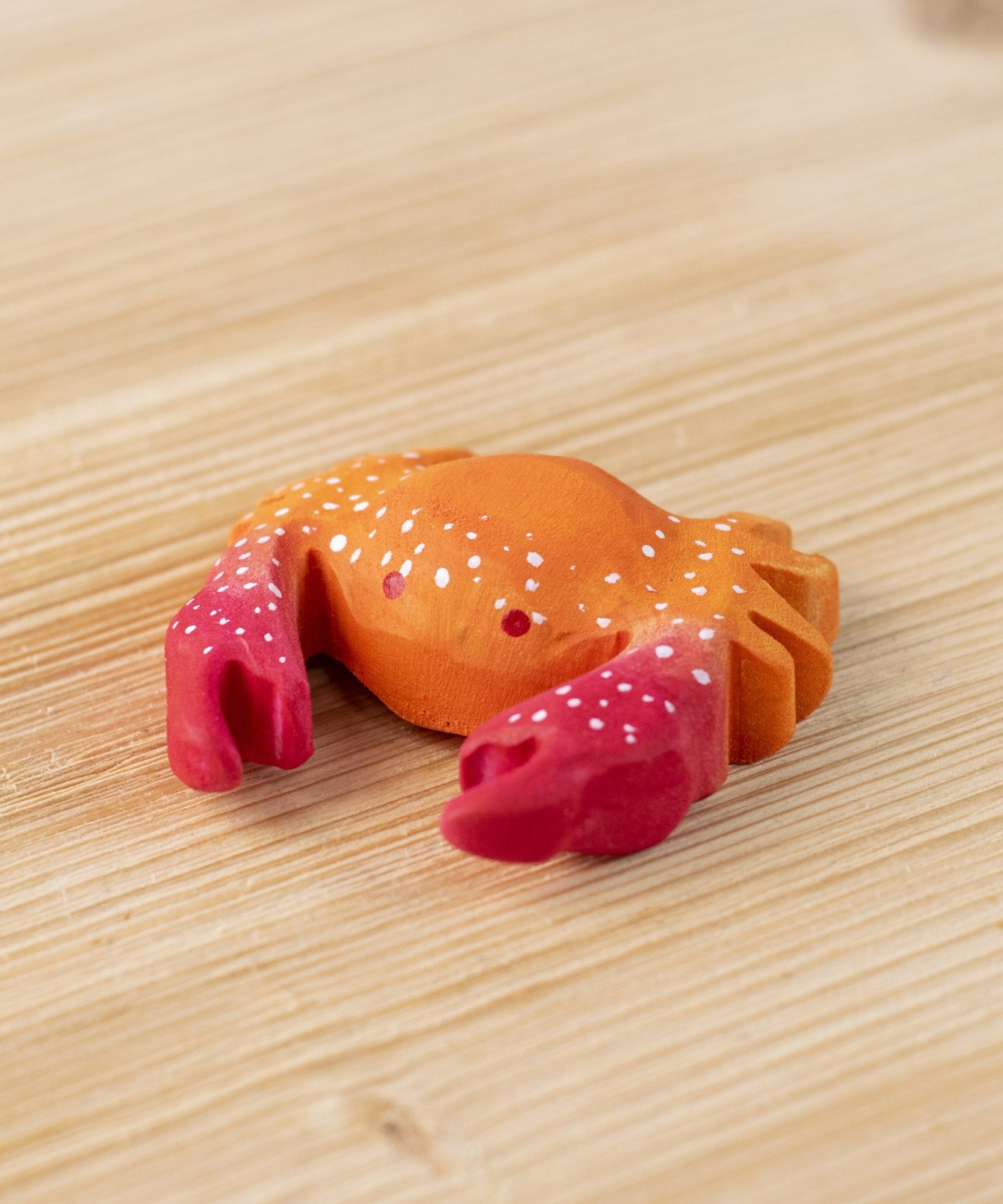 The Bumbu hand carved wooden red crab toy, with white speckled details on its shell