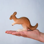 The Bumbu wooden toy kangaroo figure, held on a stretched palm to show its comparative size.