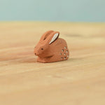 The Bumbu Toys wooden baby brown rabbit, sat in a perching position